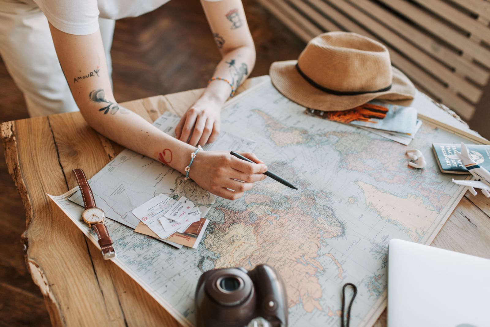 Planning travel on a world map with passport, tickets and camera — travel agent career
