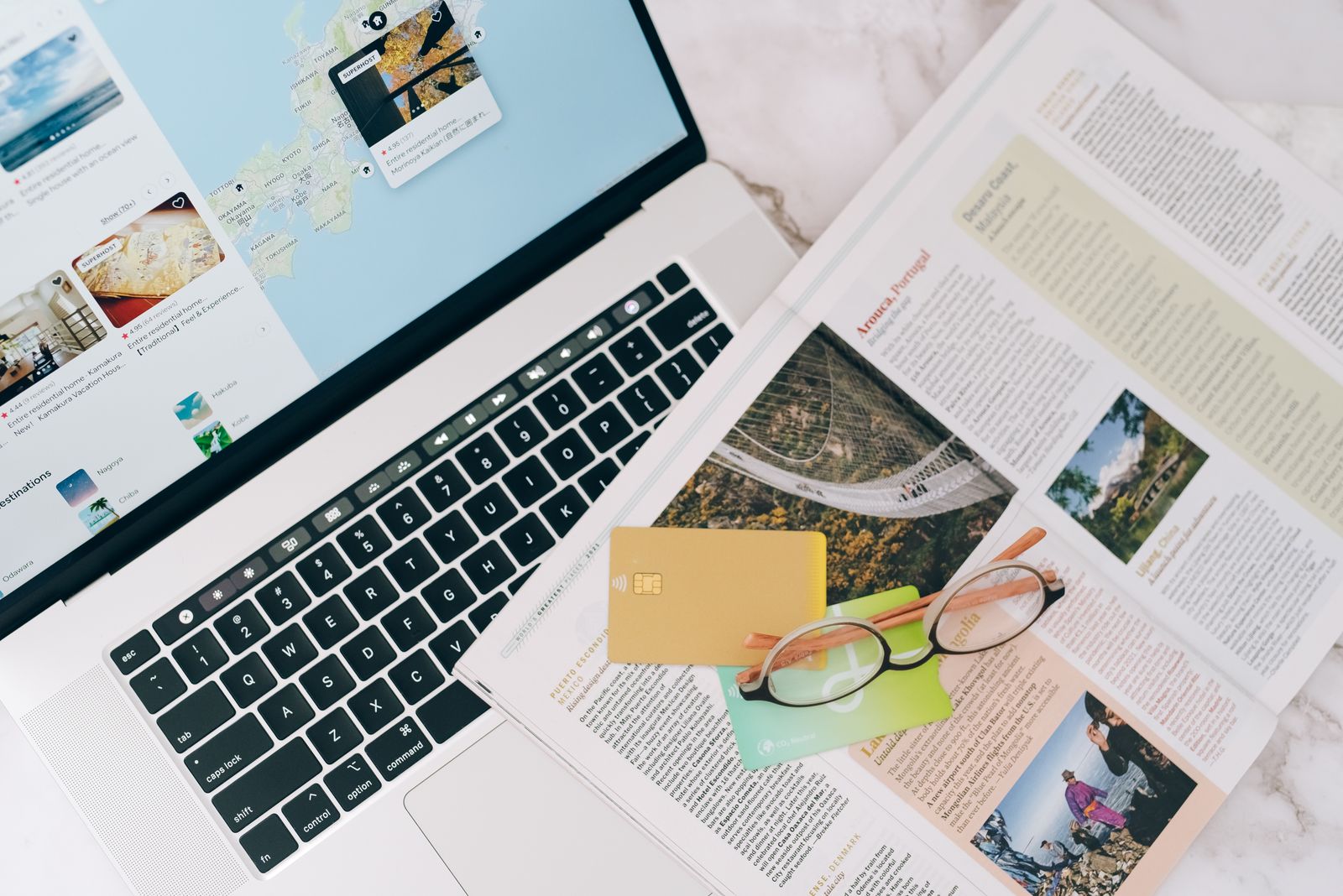 Laptop beside an open travel magazine, ready for trip planning