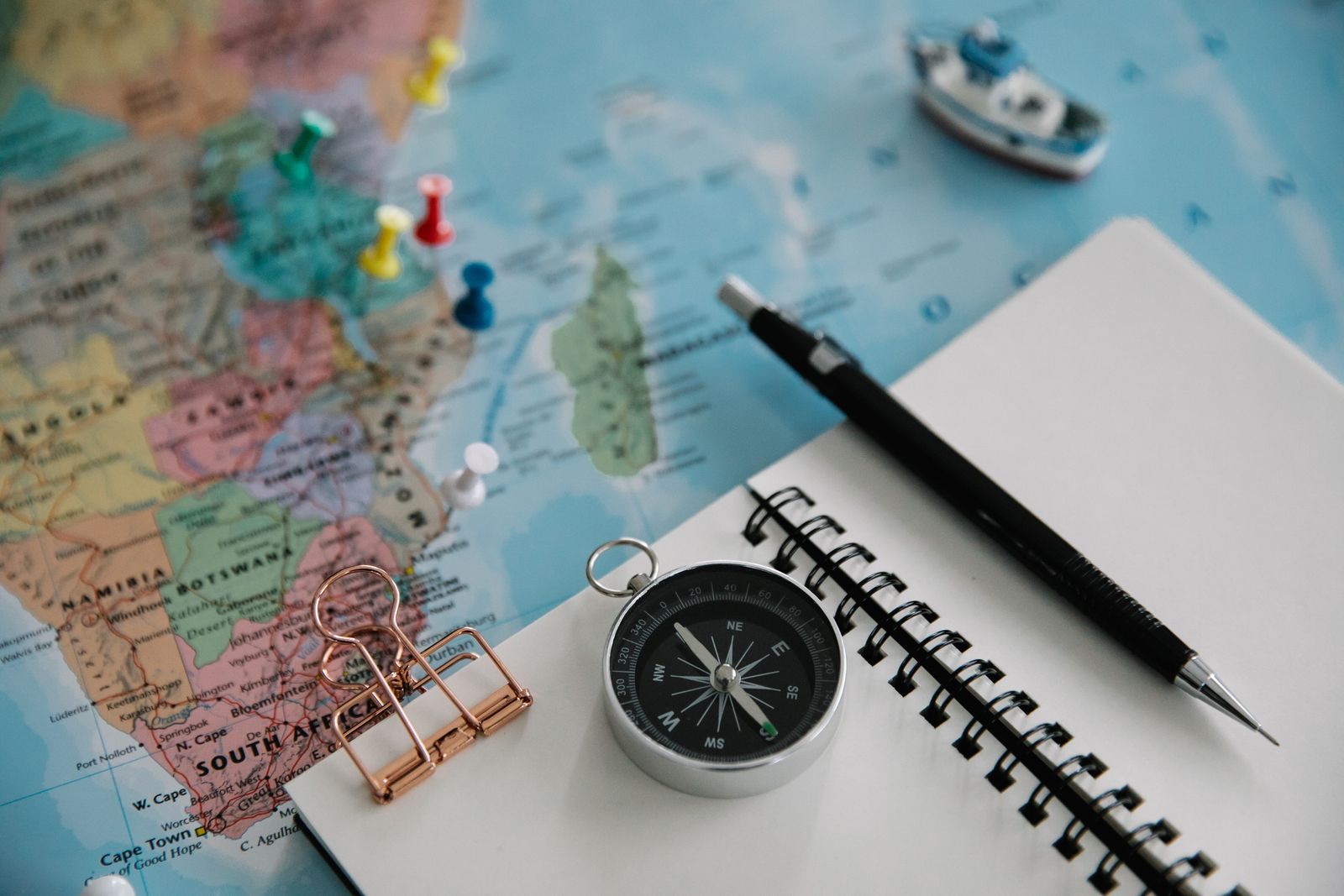 World map with pins, a notebook and a compass — planning a new travel career